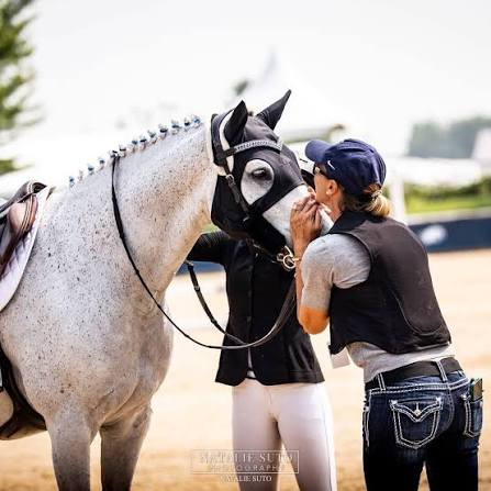 Rider embracing her grey show jumper after a class at an international show